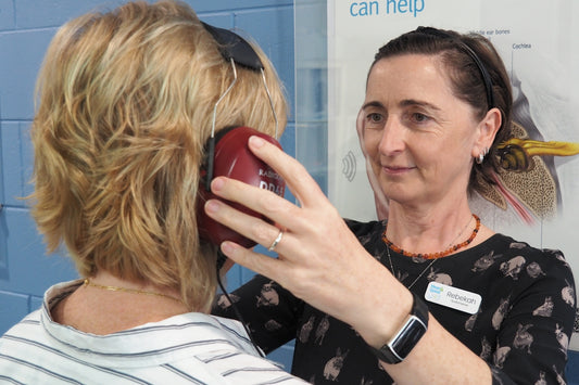 An audiologist helps a woman with a hearing test.